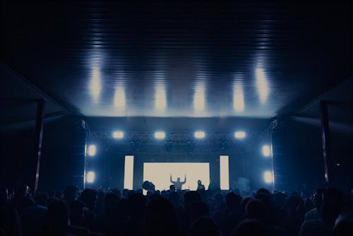 People in Front of an Illuminated Stage in a Club