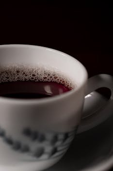 A steaming hot drink in a white ceramic cup captures attention with a dark background.