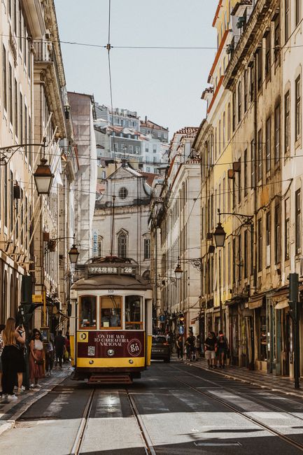 Discover the historic charm of Lisbon with its iconic tram and vibrant architecture on a sunny day.