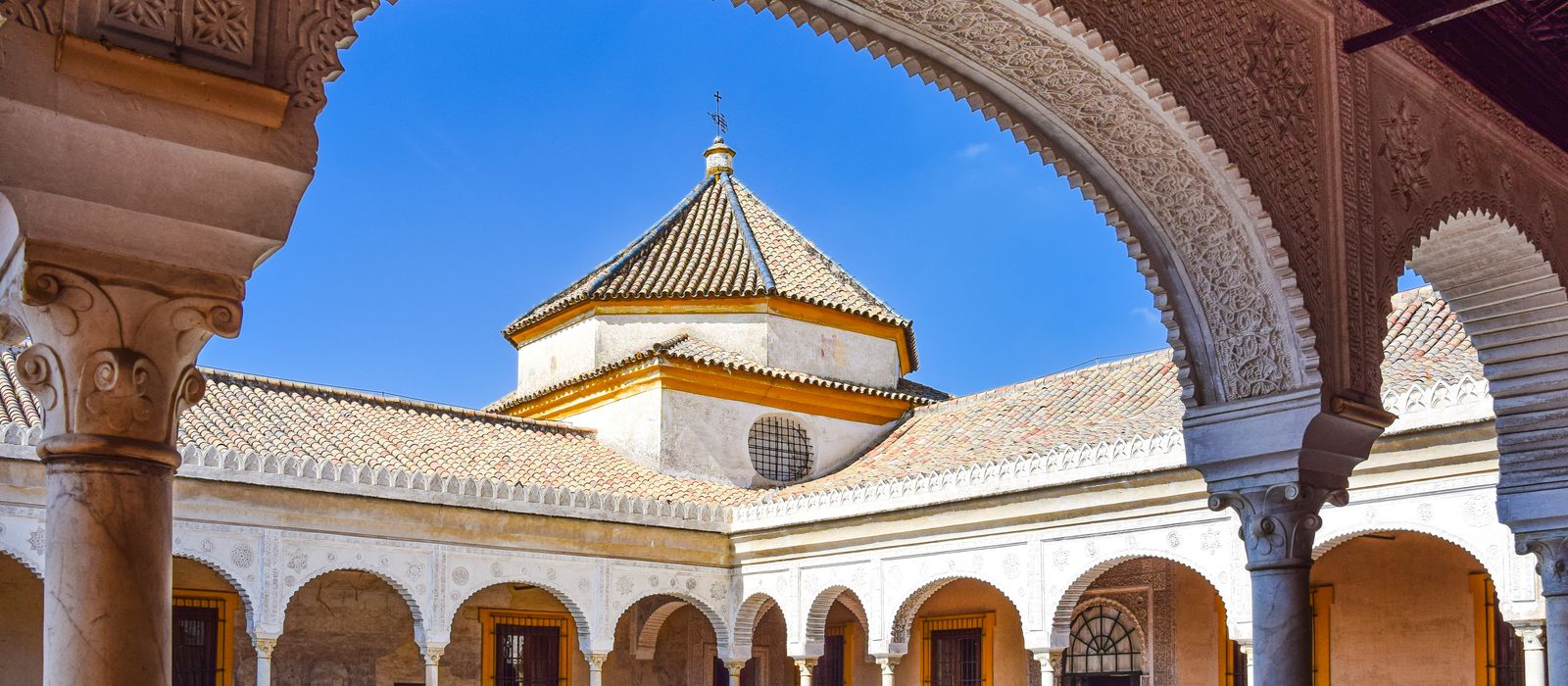 View of the ornate arches and courtyard of Casa de Pilatos in Seville, Spain.