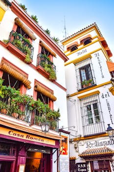 Colorful traditional Andalusian buildings with plants and decorative windows in Seville, Spain.