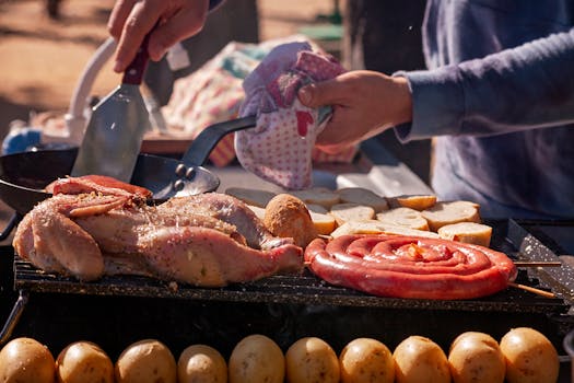 Hands preparing grilled chicken and sausages on outdoor sunny day cookout.