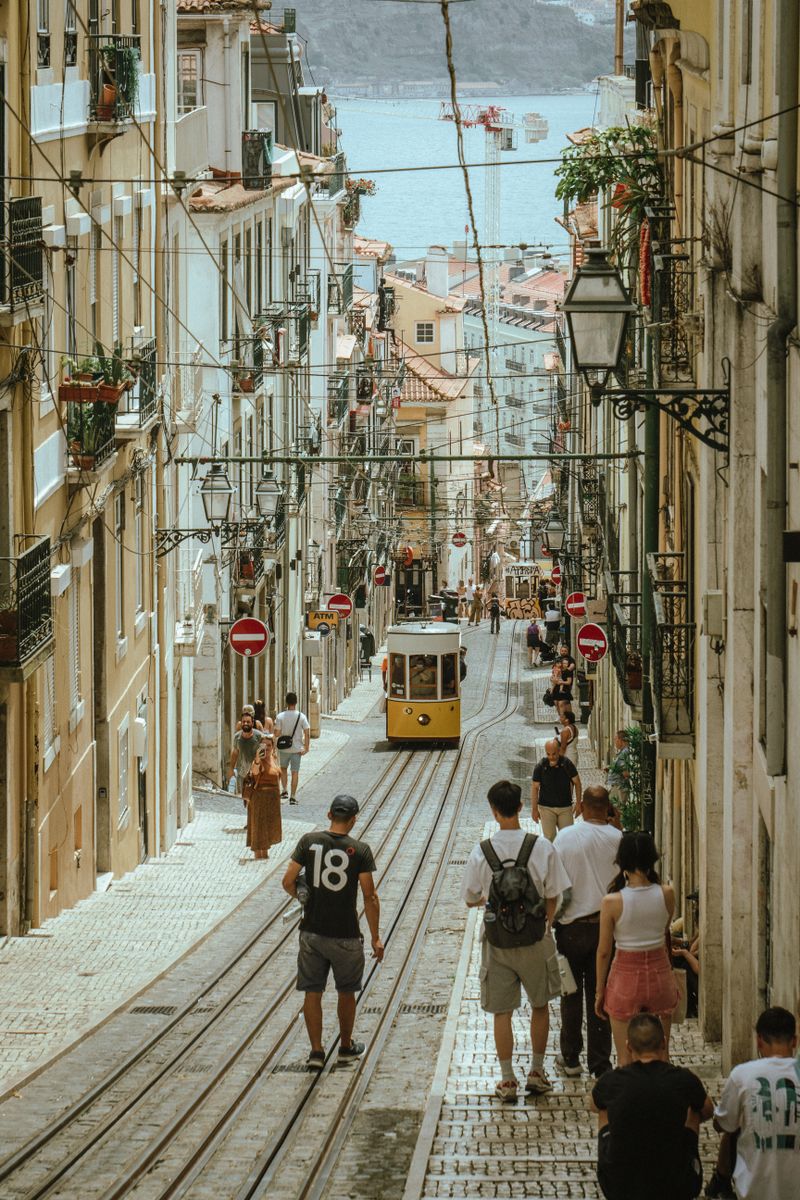People and Trams in Narrow Alley in Lisbon, Portugal · Free Stock Photo