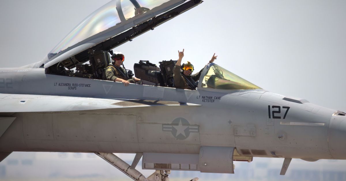 Military pilots seated in the cockpit of a fighter jet.