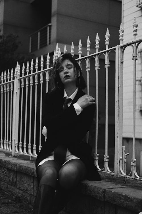 Portrait of a Young Woman Sitting on a Fenced Wall