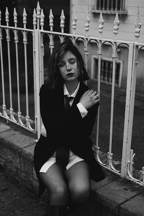 Woman in Suit Jacket Sitting Under the Fence