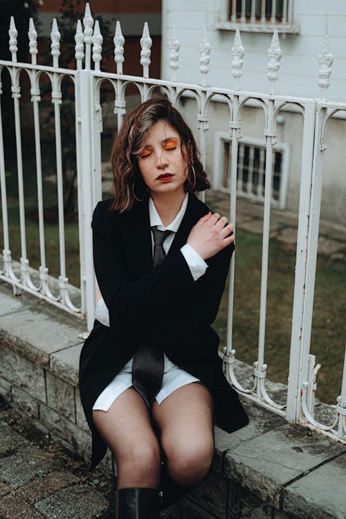 Female Model Sitting on a Fenced Wall