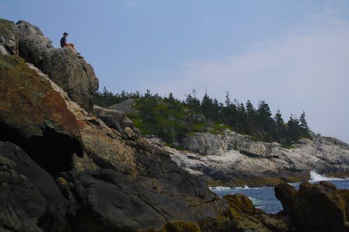 Man Sitting on Mountain Cliff
