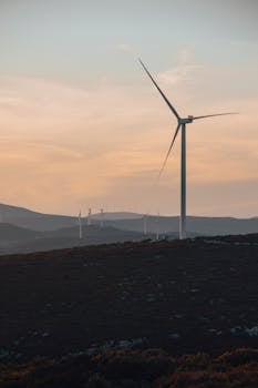 Wind turbines silhouetted against a serene sunset in Seferihisar, Izmir, capturing renewable energy in a tranquil rural landscape.