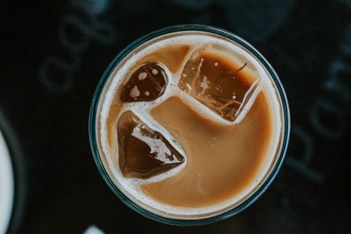 Free A close-up top view of iced coffee with ice cubes in a glass on a dark surface. Stock Photo