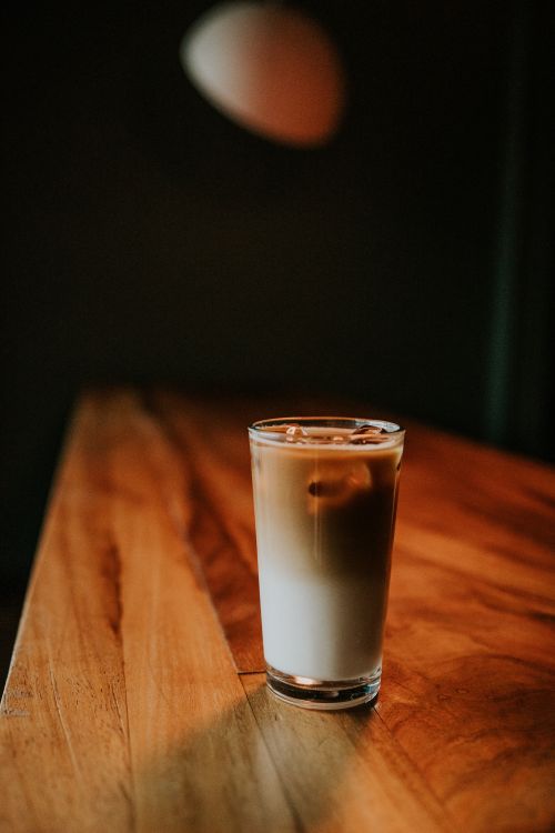 Free A refreshing glass of iced coffee on a wooden table with a dark, minimalist background. Stock Photo