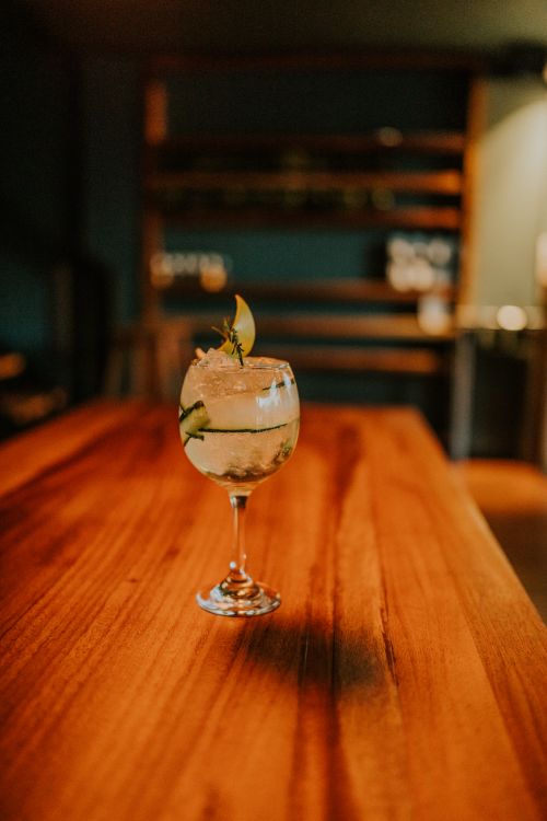 Free A refreshing cocktail garnished with lime and herbs in a glass on a wooden table at a stylish bar. Stock Photo