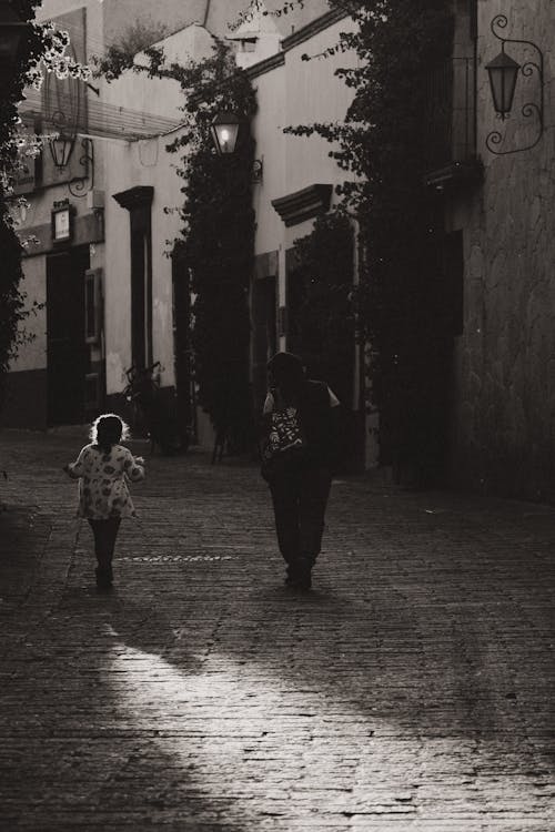 Mother with Small Daughter Walking Along the Cobbled Road