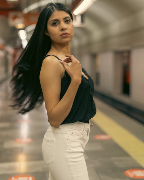 A woman in white pants standing in a subway station