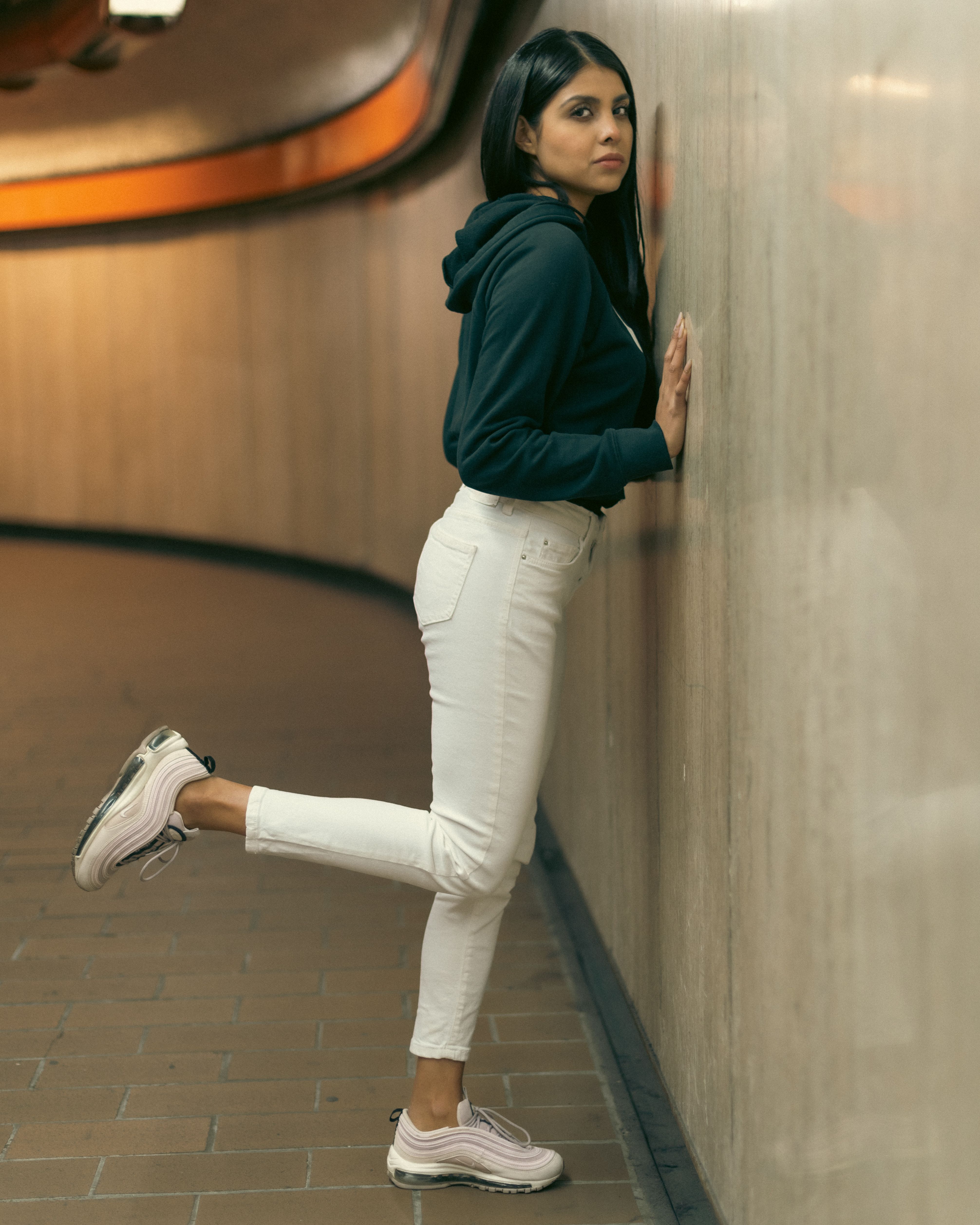 A woman leaning against a wall in white pants · Free Stock Photo