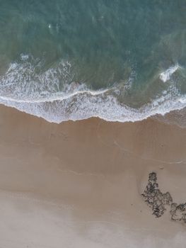 A stunning aerial shot of waves crashing on a sandy beach in Cascavel, Brazil.