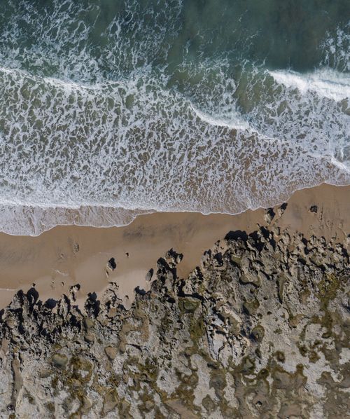 Free Drone shot of a rocky coastline in Beberibe, Brazil, showing waves crashing on the shore. Stock Photo