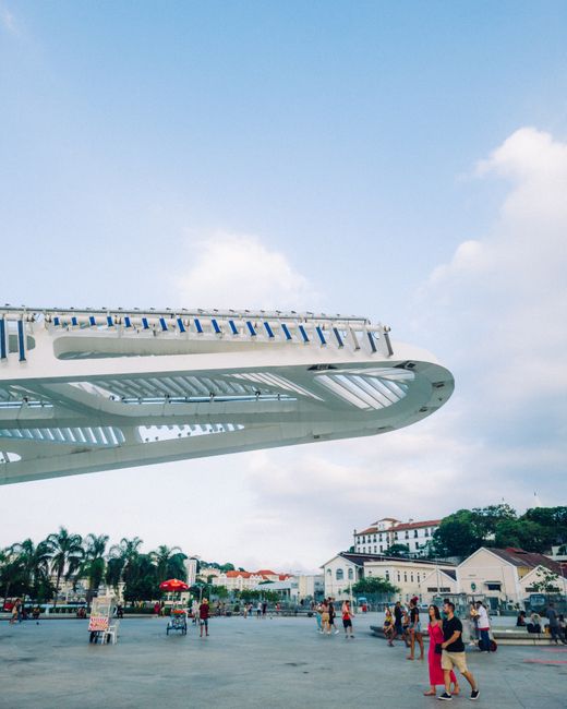 Futuristic white architecture with people in urban square under blue sky.