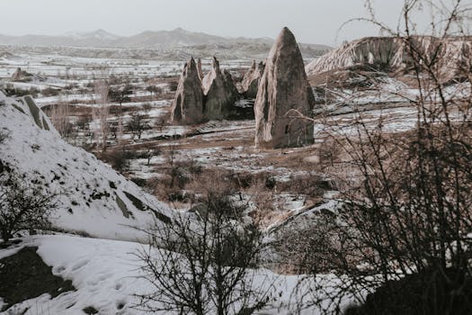 Stunning winter landscape of Cappadocia's unique rock formations under a light snowfall.