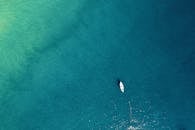 鸟瞰图中，一艘孤舟静静漂浮在绿松石般平静的水面上，尽显宁静