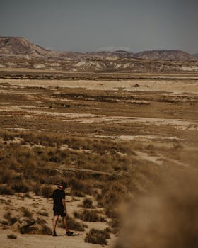 A lone traveler walks through the arid landscape of Bardenas Reales in summer.