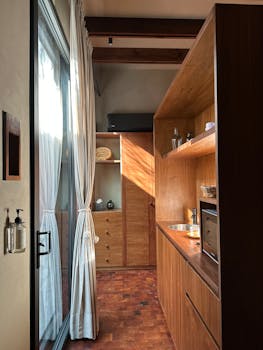 Bright and elegant small kitchen with wood cabinetry and natural light streaming through glass doors.