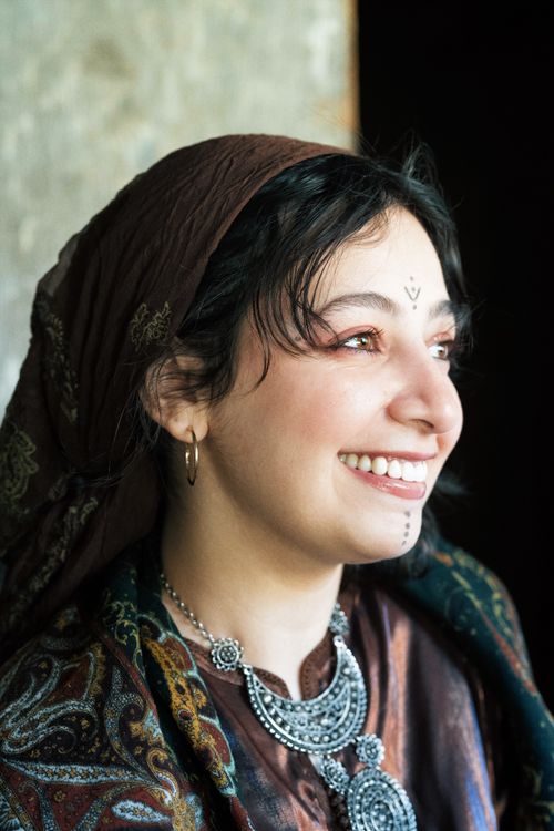 Free Portrait of a smiling woman in traditional attire with a headscarf and ornamental necklace. Stock Photo