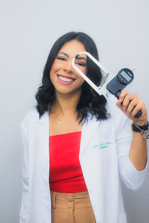 Woman in a White Jacket Standing and Holding an Electronic Device 