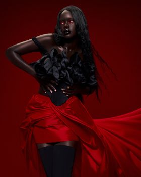 Striking studio portrait of a woman in a black dress and red skirt, exuding elegance and power.