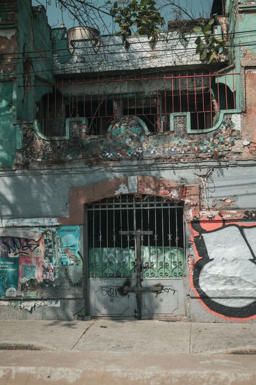 Free Neglected urban building with colorful graffiti and foliage in Ciudad de México, showcasing an artistic urban scene. Stock Photo
