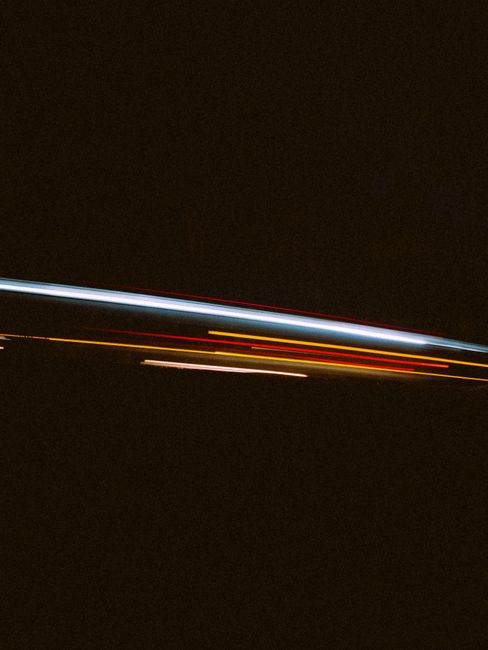 Vibrant and colorful light trails in motion against a stark dark background, creating an abstract and dynamic visual effect.