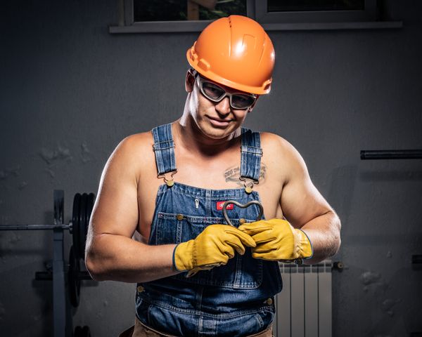 Construction worker in overalls and helmet at an indoor site
