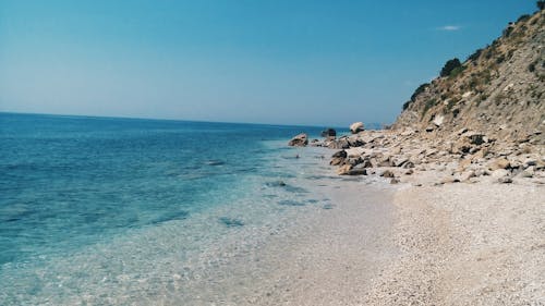 免费 白天蓝色海滩附近的灰色岩层 素材图片