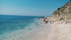 阳光明媚的天空下，美丽清澈的蓝色海洋与岩石海岸线相遇