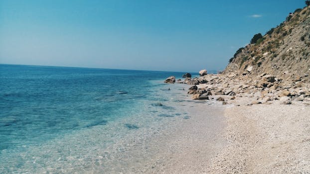 阳光明媚的天空下，美丽清澈的蓝色海洋与岩石海岸线相遇