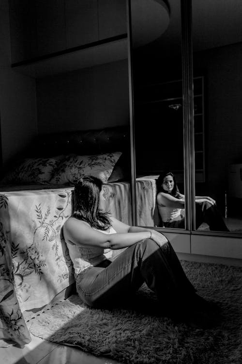 Woman Sitting by Bed and Mirror on Wardrobe