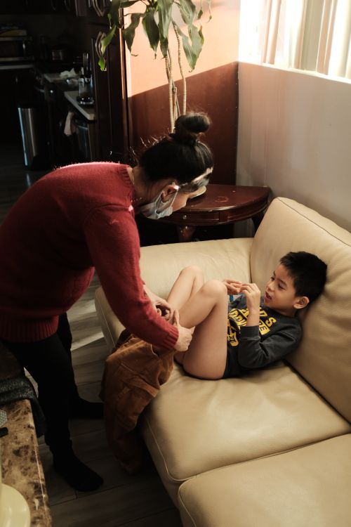 Free the mother helps child put on a  pant  Stock Photo