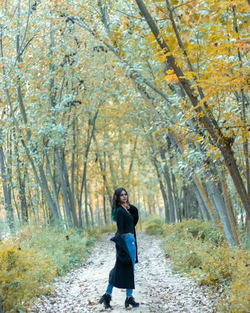 Young Woman Standing on the Road in a Forest 