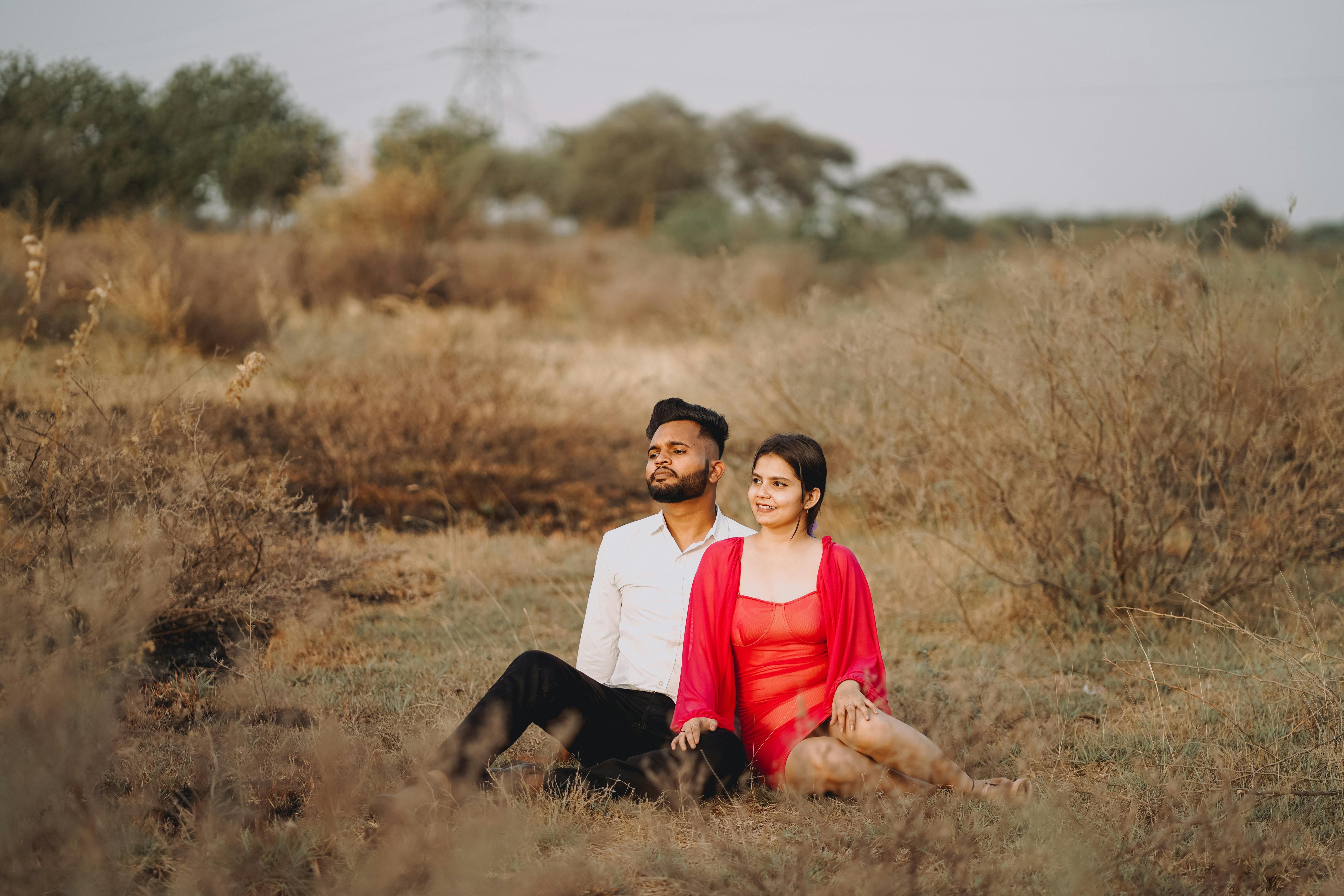 A couple sitting closely in a green field, reflecting a sense of harmony and connection.