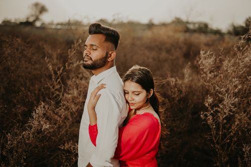 Free A young couple embracing in a romantic sunny field setting, depicting love and togetherness. Stock Photo