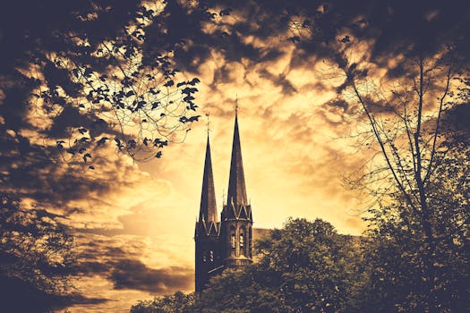哥特式教堂的尖顶在树木环绕的日落天空中耸立