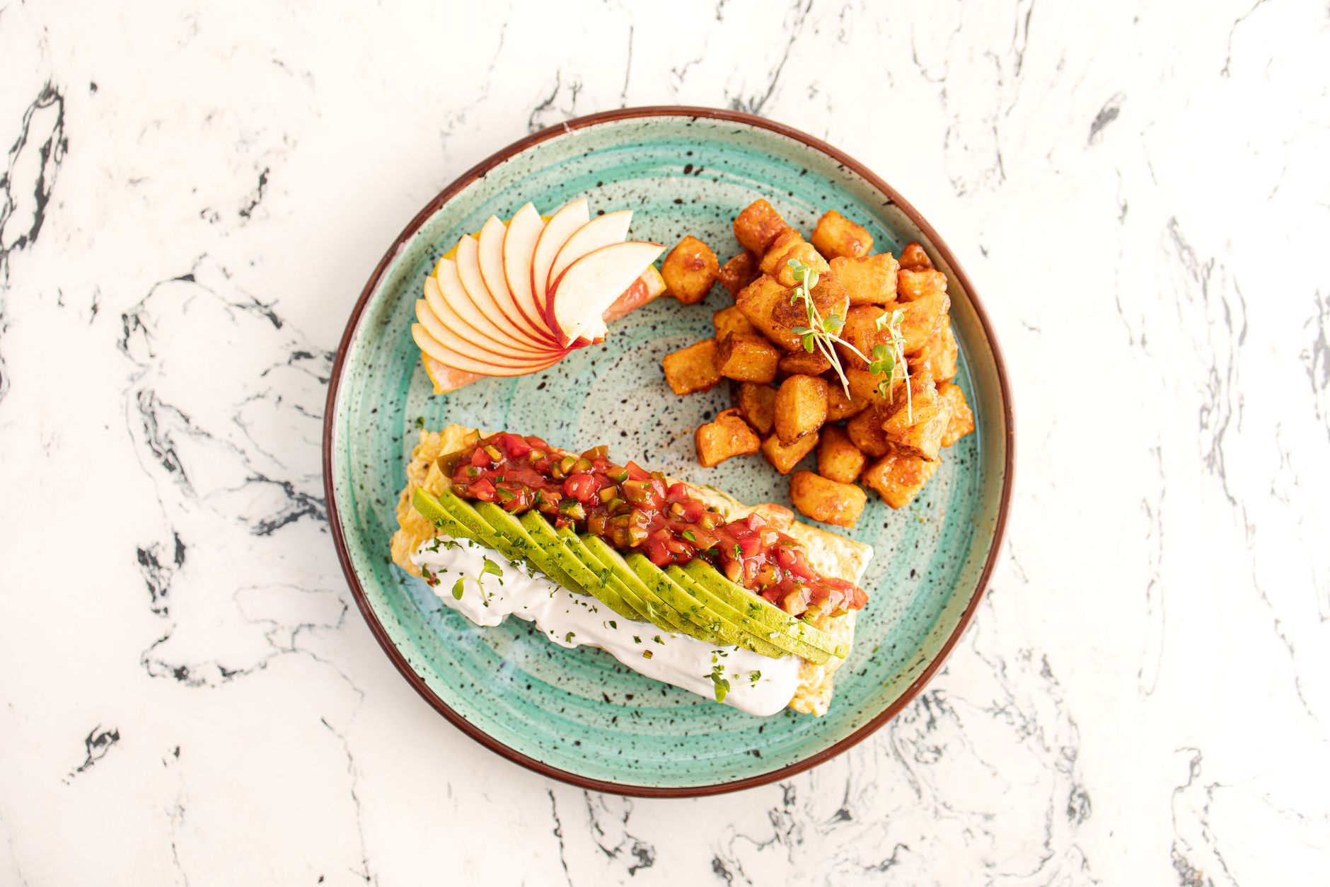 Delicious avocado toast with apples and crispy potatoes on a turquoise plate.