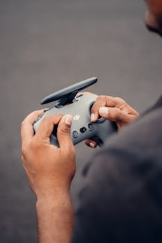 Hands holding a drone controller with focus on touch and technology in an outdoor setting.