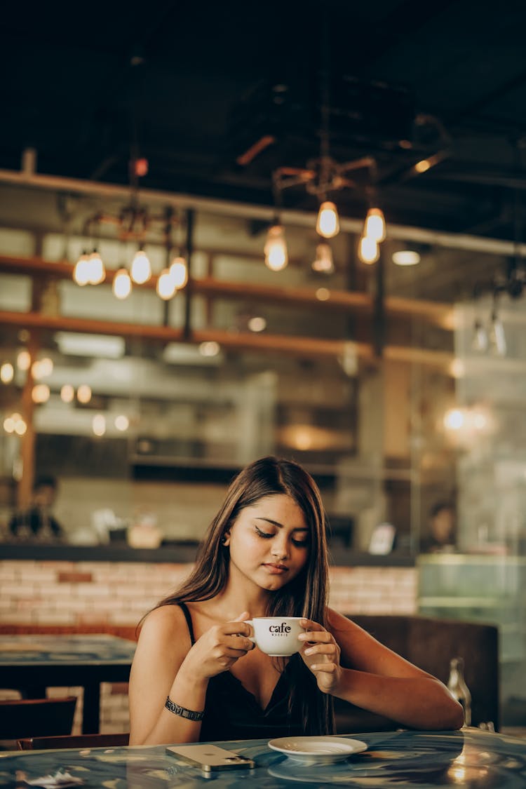 Girl With Coffee Sitting At Cafe Table