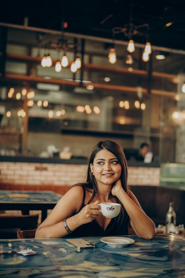 Smiling Girl With Coffee Sitting At Cafe Table