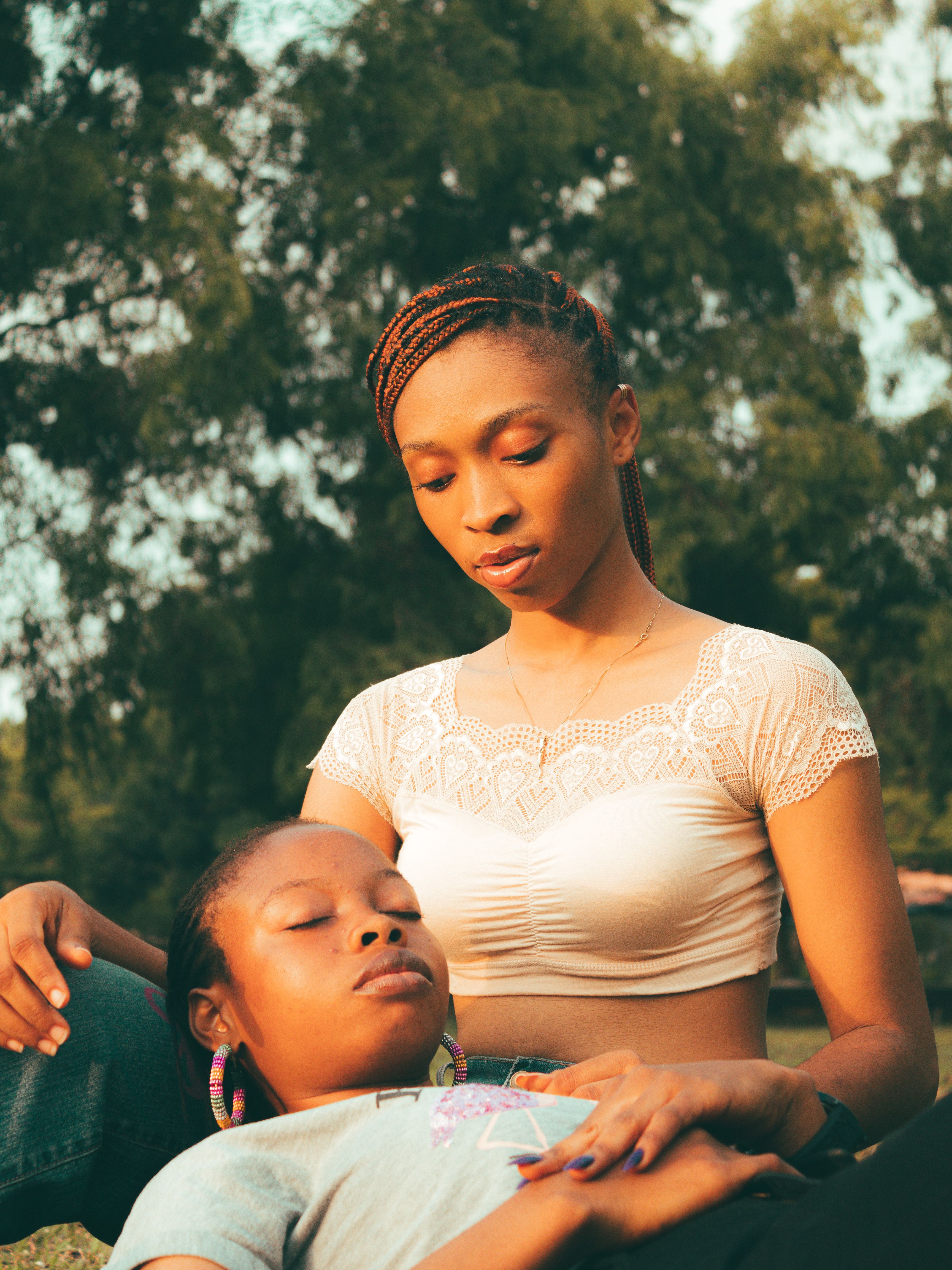 A tender moment outdoors with one woman lying on another's lap, expressing warmth and closeness.
