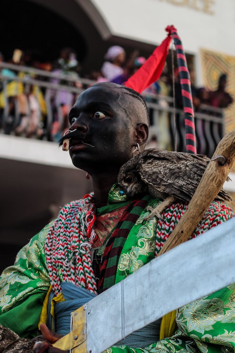 Man In Traditional Clothing Posing On Parade With Bird On Shoulder