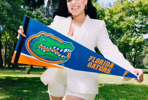 Smiling woman outdoors holding a Florida Gators banner. Bright and lively setting in Florida, United States.