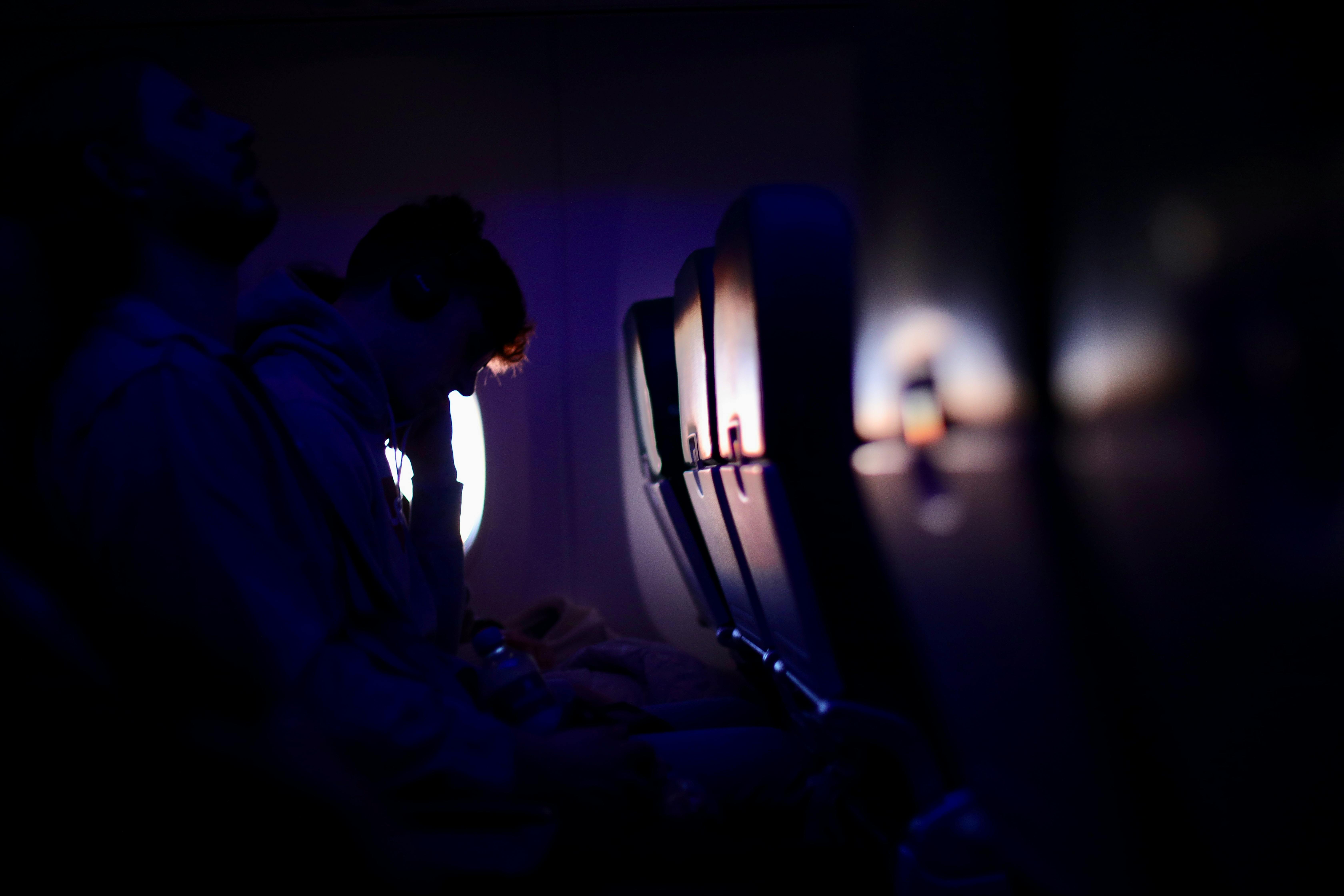 Passengers resting in a dimly lit airplane with purple ambient lighting, showcasing a peaceful travel experience.