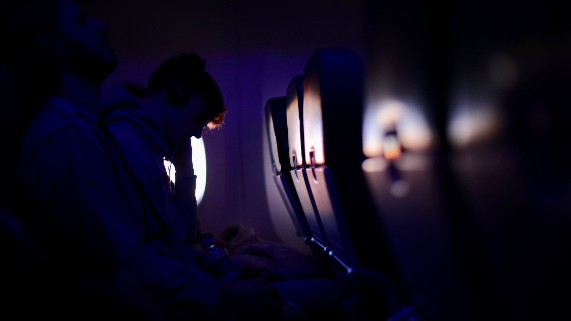 Modafinil for Long Haul Flights: Your Ultimate Guide Passengers resting in a dimly lit airplane with purple ambient lighting, showcasing a peaceful travel experience — modafinil for long haul flights